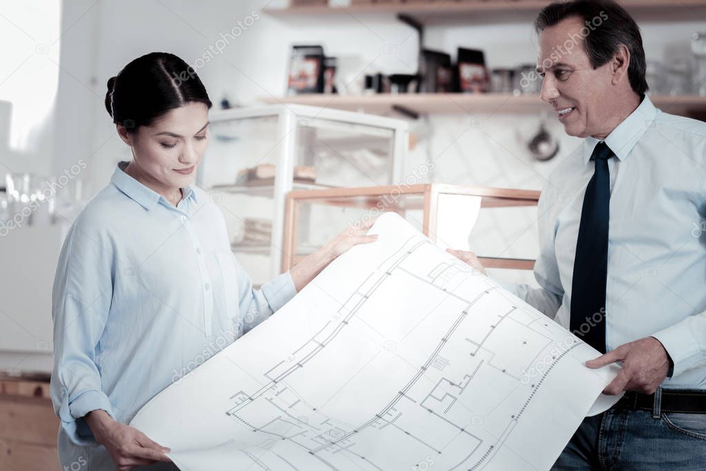 Curious engineers smiling and looking at the blueprint