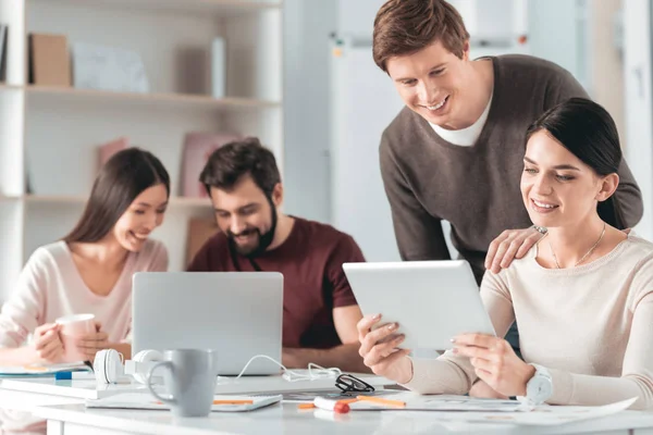 Mujer joven agradable mirando la pantalla de la tableta — Foto de Stock