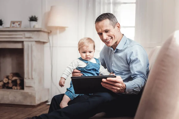 Netter positiver Mann, der seinem Baby ein Spiel zeigt — Stockfoto