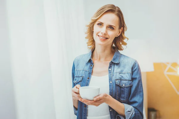 Relajada joven mujer sosteniendo la taza en ambas manos — Foto de Stock