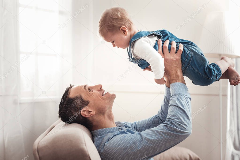 Joyful happy man spending time with his baby