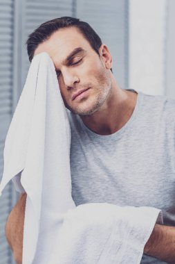 Gri tişörtlü beyaz havlu tutan esmer adam