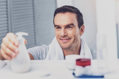 Esmer adam sıvı sabun rafa koyarak