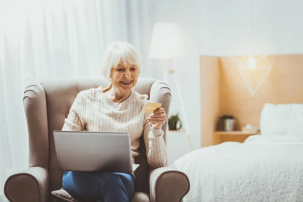 Mujer mayor satisfecha mirando fijamente la tarjeta de crédito — Foto de Stock