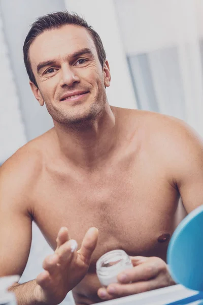 Pleasant looking man with face cream in his hands — Stock Photo, Image