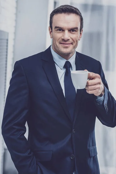 Empreendedor agradável segurando uma xícara com café — Fotografia de Stock