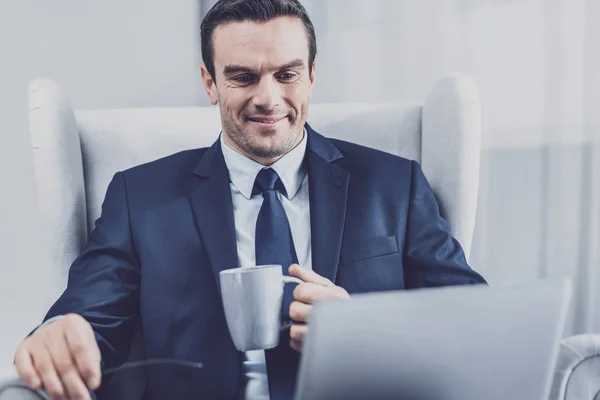 Hombre sonriente sentado en la oficina con una taza de té — Foto de Stock