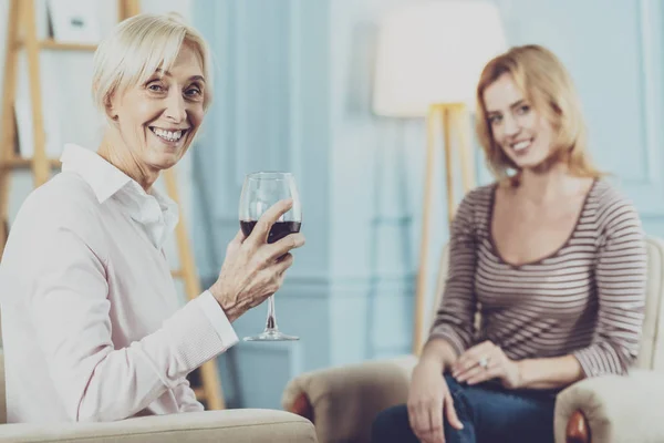 Donna anziana positiva con un bicchiere di vino in mano — Foto Stock