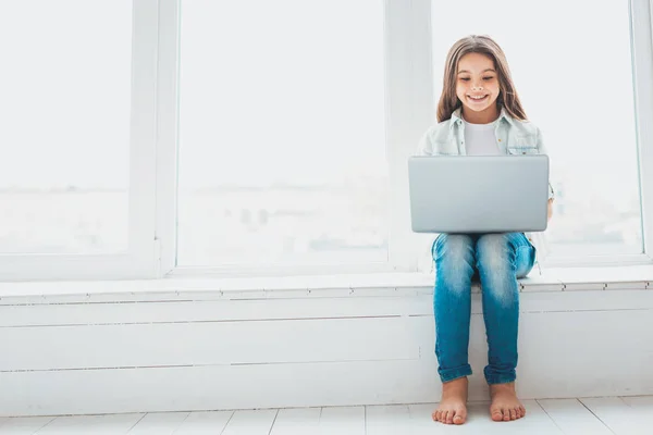 Langharige schoolmeisje zittend op de vensterbank thuis — Stockfoto