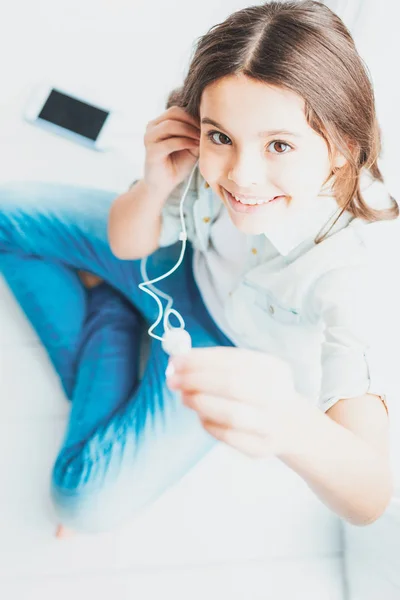 Dcera sedí na podlaze při poslechu hudby z chytrého telefonu — Stock fotografie