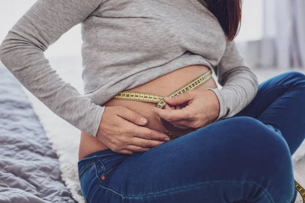 Крупный план беременной очаровательной женщины измерения ее желудка — стоковое фото