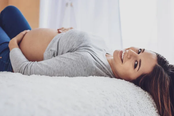 Glada fantastiska gravid kvinna liggande på sängen — Stockfoto