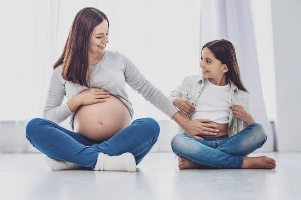 Mujer embarazada optimista tocando su estómago hijas — Foto de Stock