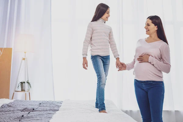 Chica encantada mirando a su madre embarazada — Foto de Stock