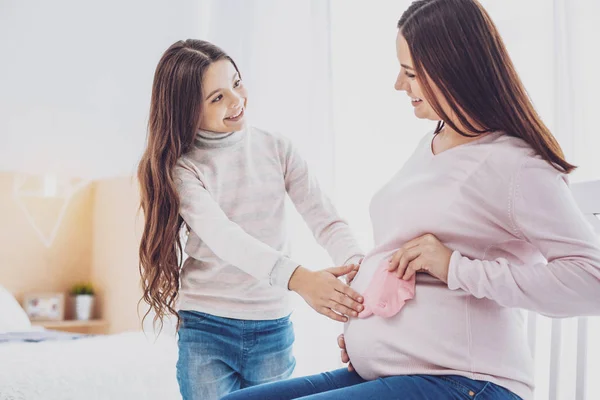 Талія оптимістичної вагітної жінки, що показує рожеві шкарпетки дочці — стокове фото