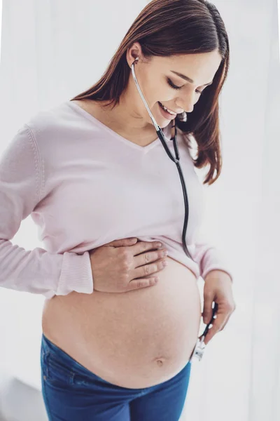 Pleased pregnant woman listening her stomach — Stock Photo, Image