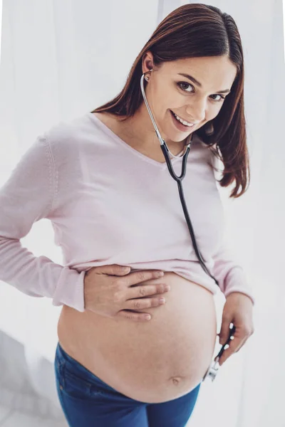 Задоволена вагітна жінка з медичними навушниками — стокове фото