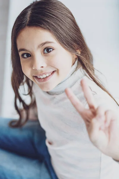 Portrait of charming pleased girl showing two fingers