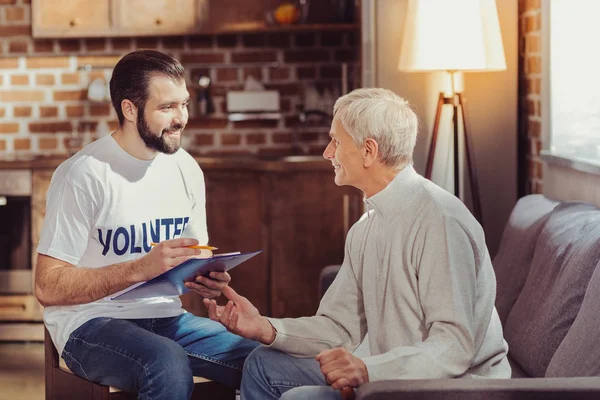 Vriendelijke knappe vrijwilligers houden een tablet en schrijven. — Stockfoto