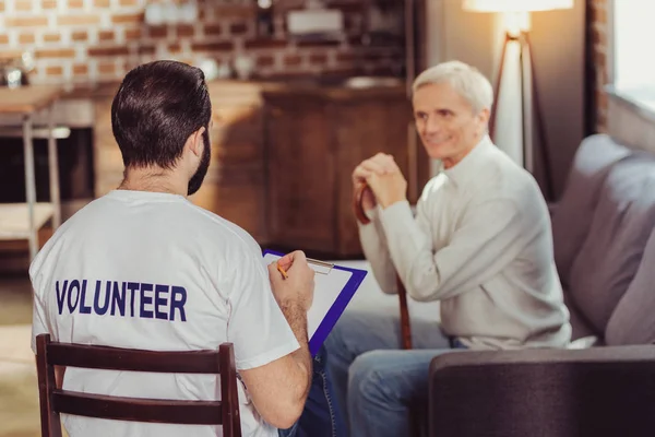 Intelligent uppmärksam volontär skriva och lyssna på en pensionerad. — Stockfoto