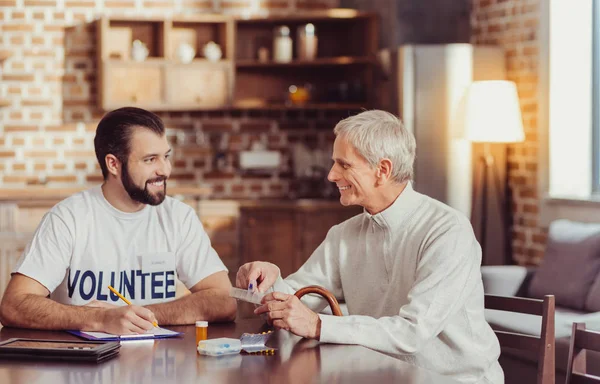 Lycklig senior man sitter vid bordet och hålla piller. — Stockfoto