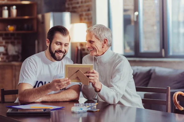 Intresserad av uppmärksam man ler och tittar på ett foto. — Stockfoto