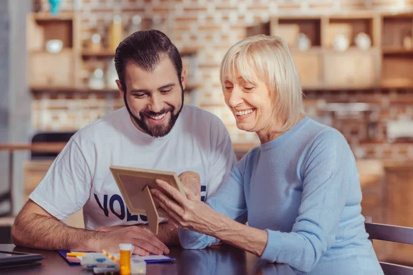 Nöjd söt kvinna ler och visar ett foto. — Stockfoto