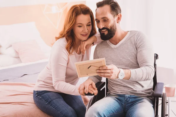 Pareja positiva mirando un marco de fotos — Foto de Stock