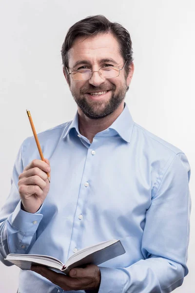 Yakışıklı bir gülümseyen sakallı adam kalem ve defter tutan — Stok fotoğraf