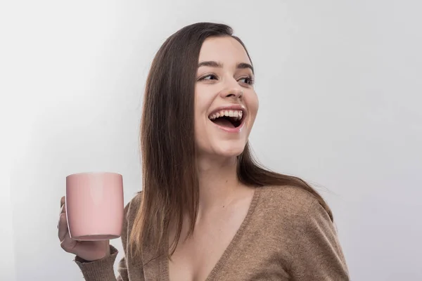 Сияющая привлекательная женщина держит розовую чашку с горячим вкусным чаем — стоковое фото