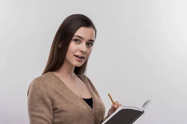 Beautiful young businesswoman holding pencil and notebook — Stock Photo, Image