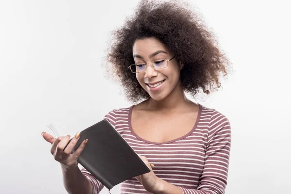 Smart smiling pleasant curly woman holding her black notebook — Stock Photo, Image