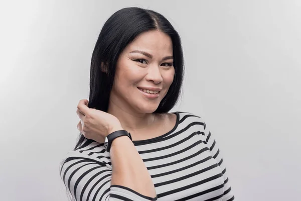 Mujer radiante de cabello oscuro sosteniendo un reloj inteligente en su mano —  Fotos de Stock