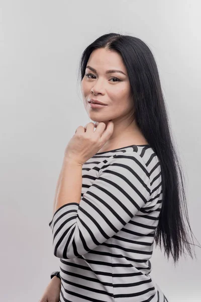 Mujer de ojos oscuros con el pelo largo y liso de pie delante de la pared blanca — Foto de Stock