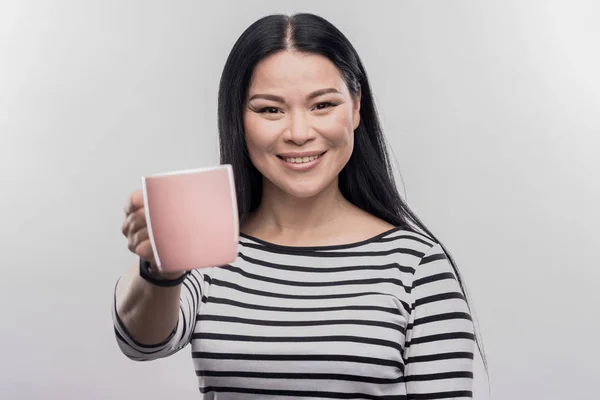 Glimlachend aantrekkelijk zakenvrouw houden van roze cup met warme koffie — Stockfoto