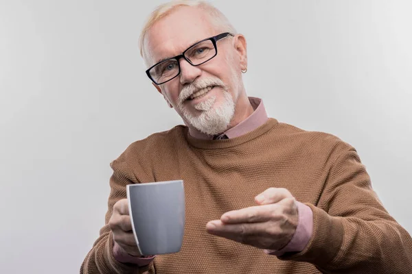 Kind-hearted aged office manager offering cup of tea his colleague