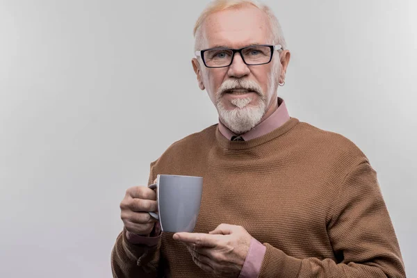 Uomo d'affari anziano con gli occhiali in mano tazza blu con tè caldo — Foto Stock