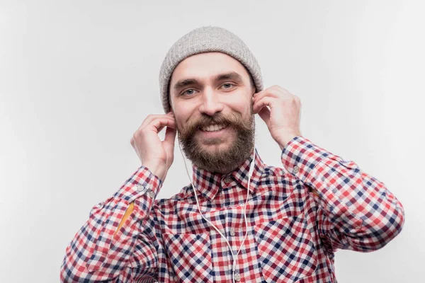 Stylish dark-haired man using earphone while listening to music — Stock Photo, Image