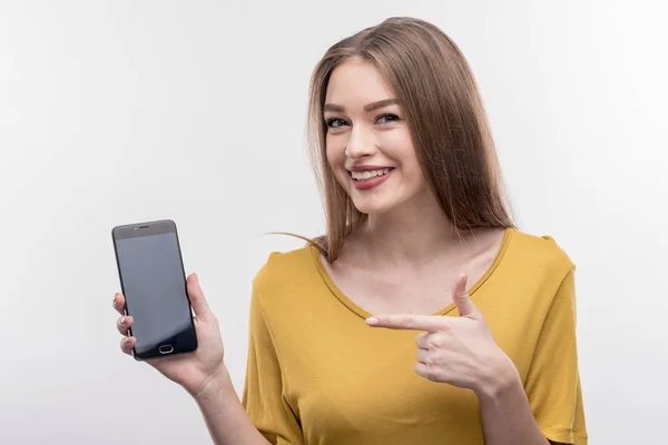 Agradable mujer rubia positiva sosteniendo su teléfono inteligente negro — Foto de Stock