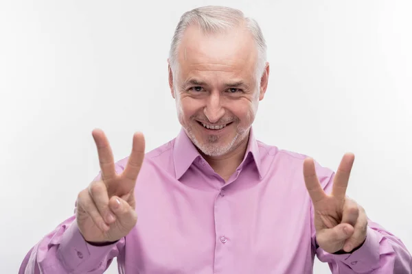 Smiling mature man with facial wrinkles showing peace sign — Stock Photo, Image
