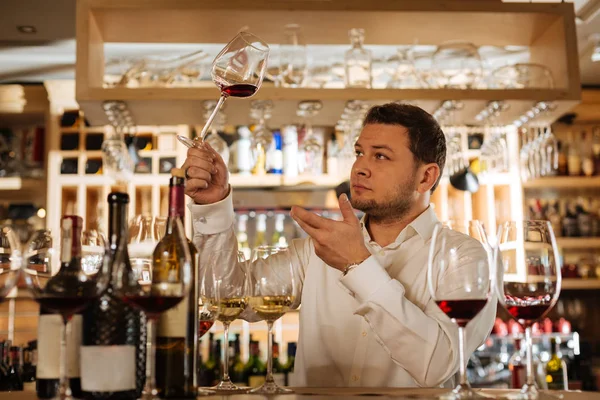 Smart nice man looking at the wine — Stock Photo, Image