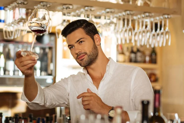 Encantado homem positivo olhando para o copo com vinho — Fotografia de Stock