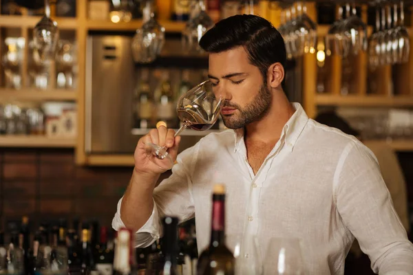 Agradable hombre guapo disfrutando del olor del vino — Foto de Stock