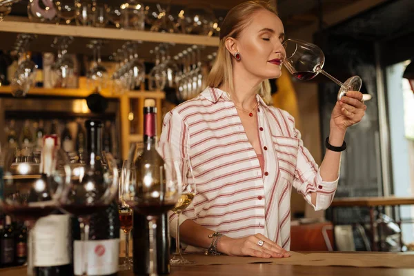 Nice delighted woman enjoying the wine smell