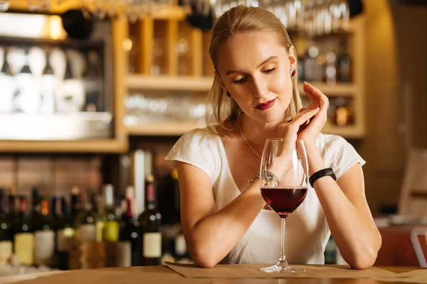 Восхитительная позитивная женщина сидит перед бокалом вина — стоковое фото