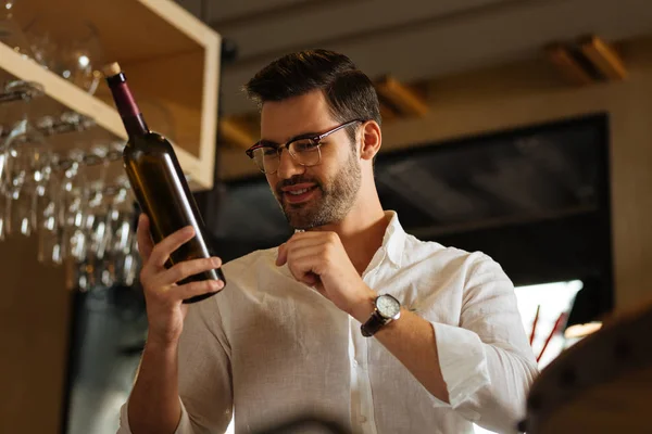 Alegre buen hombre estudiando la botella de vino — Foto de Stock