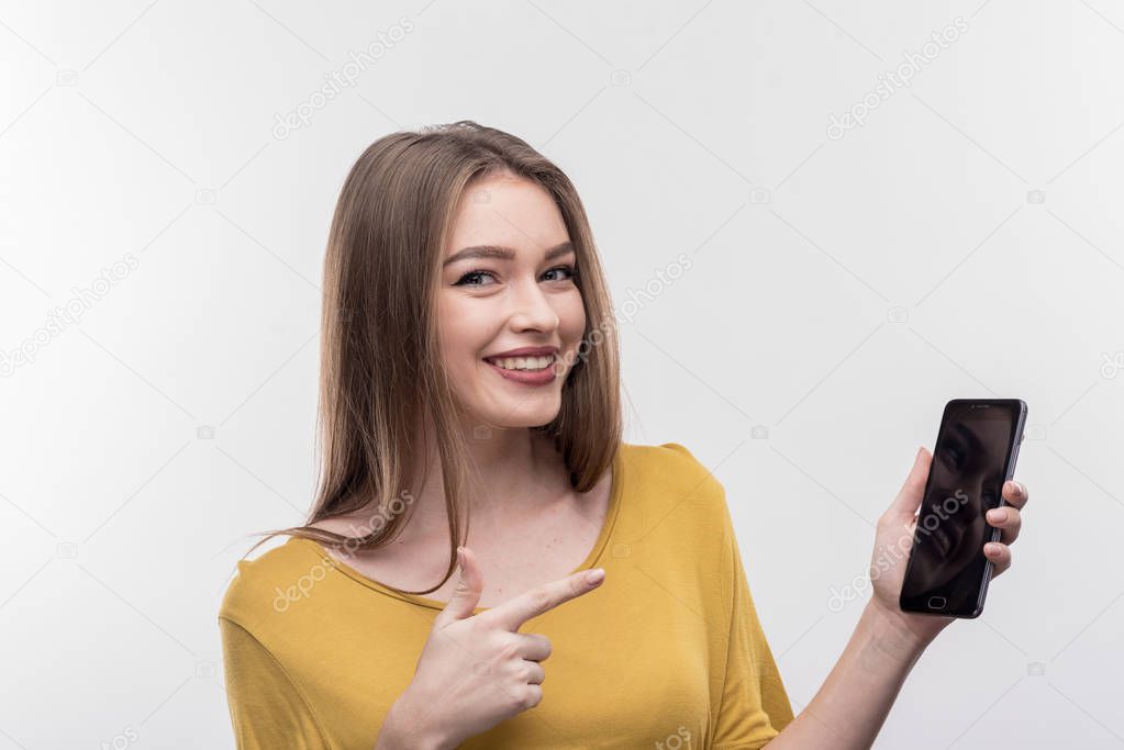 Smiling blonde-haired woman holding her phone while calling friends