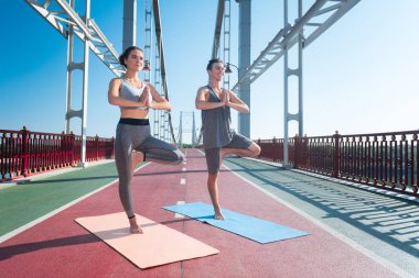 Yoga sırasında Dengeleme antrenörü ve iyimser kadın