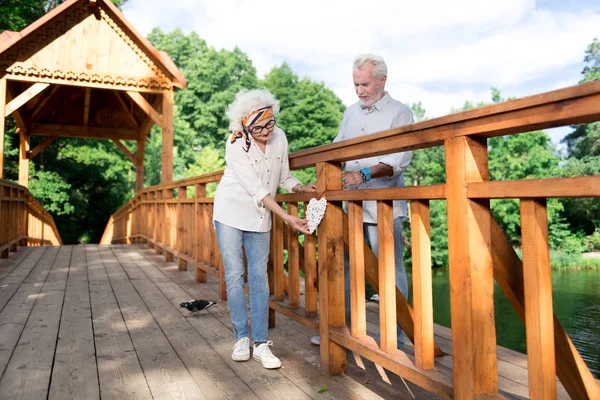 Pareja de pensionistas mostrando al mundo amor eterno colgando de corazón en puente — Foto de Stock