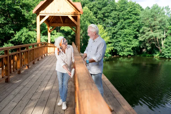 Radiante anciano y mujer de pie en el puente en el bosque — Foto de Stock